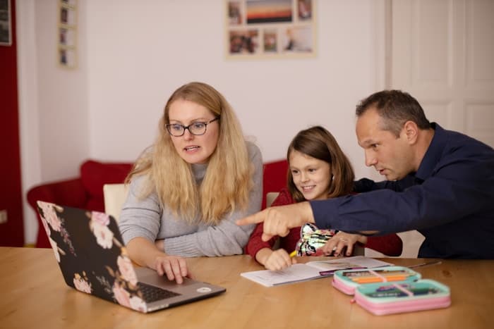 A family gathered around a laptop at a table, reviewing a plan together.